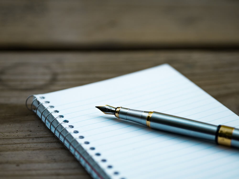 Picture of a pen resting on a notebook.