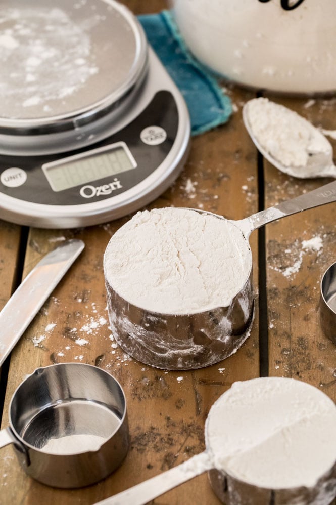 Flour in a silver measuring cup with scale in the background