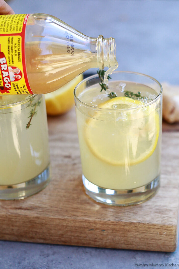 Bragg apple cider vinegar gets poured into a glass with water and lemon for a tasty apple cider vinegar drink recipe. 