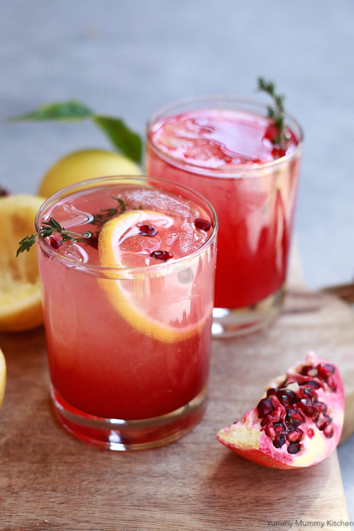 Apple cider vinegar drinks with lemon and pomegranate juice on a cutting board. 