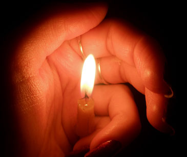 Церковная свеча прикрыта женской рукой
