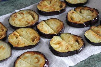 Обжаренные баклажаны на бумажных салфетках для салата с помидорами