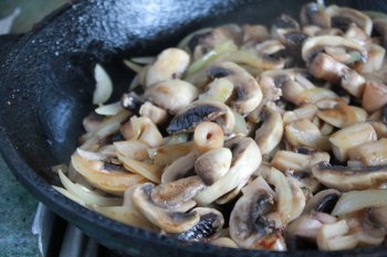 Шампиньоны и лук жарятся на сковороде для салата с баклажанами