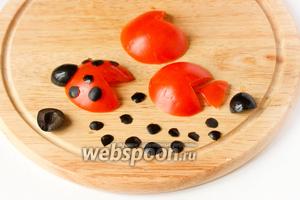 Теперь подготовим «божьих коровок». С помидора срезаем одну сторону и вырезаем с одной стороны треугольник — получится «тельце с крыльями». Получается, что у одного помидора мы берём 2 части (2 стороны срезаем), а у ещё одного только одну. Из маслин вырезаем «головы» и пятна на тельце.