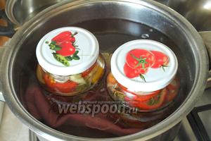 В большую кастрюлю налить горячую воду, на дно положить тканевую салфетку и поставить банки. Вода должна доходить по плечики. Накрыть банки кипячёнными крышками. Стерилизовать салат 10 минут с момента закипания воды.