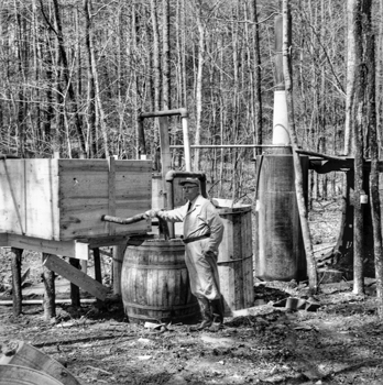 A law enforcement officer pauses after a raid on an illegal liquor distillery in the Eno Township of Orange County in 1958. Photograph by Roland Giduz. North Carolina Collection, University of North Carolina at Chapel Hill Library.