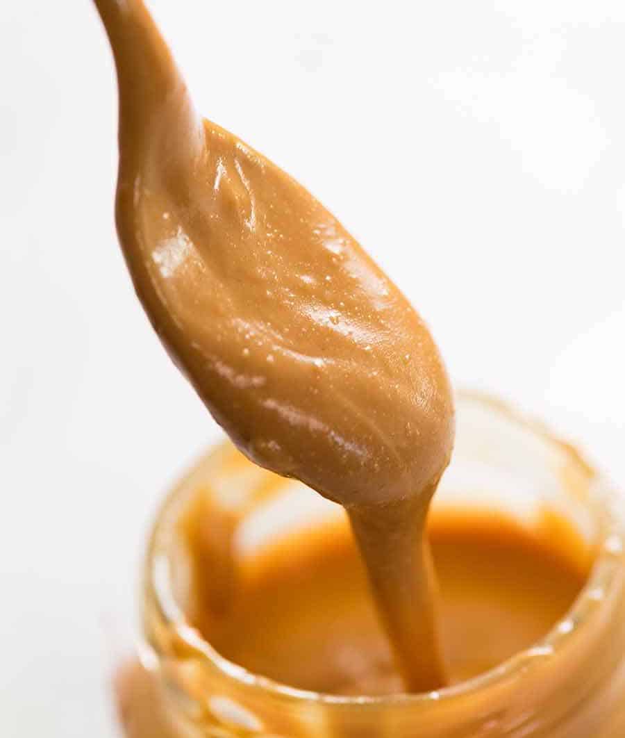 Spoon scooping pure, natural peanut butter from jar